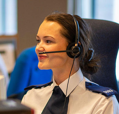 Image of Female Police Staff Member with phone headset on in the call centre