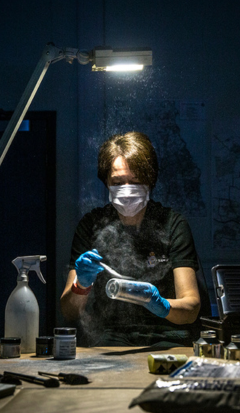 Northumbria Police staff member wearing a mask and blue gloves doing forensic work in a lab