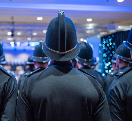 Police Officers wearing black uniform and hats facing away from the camera at a celebration event for completion of training